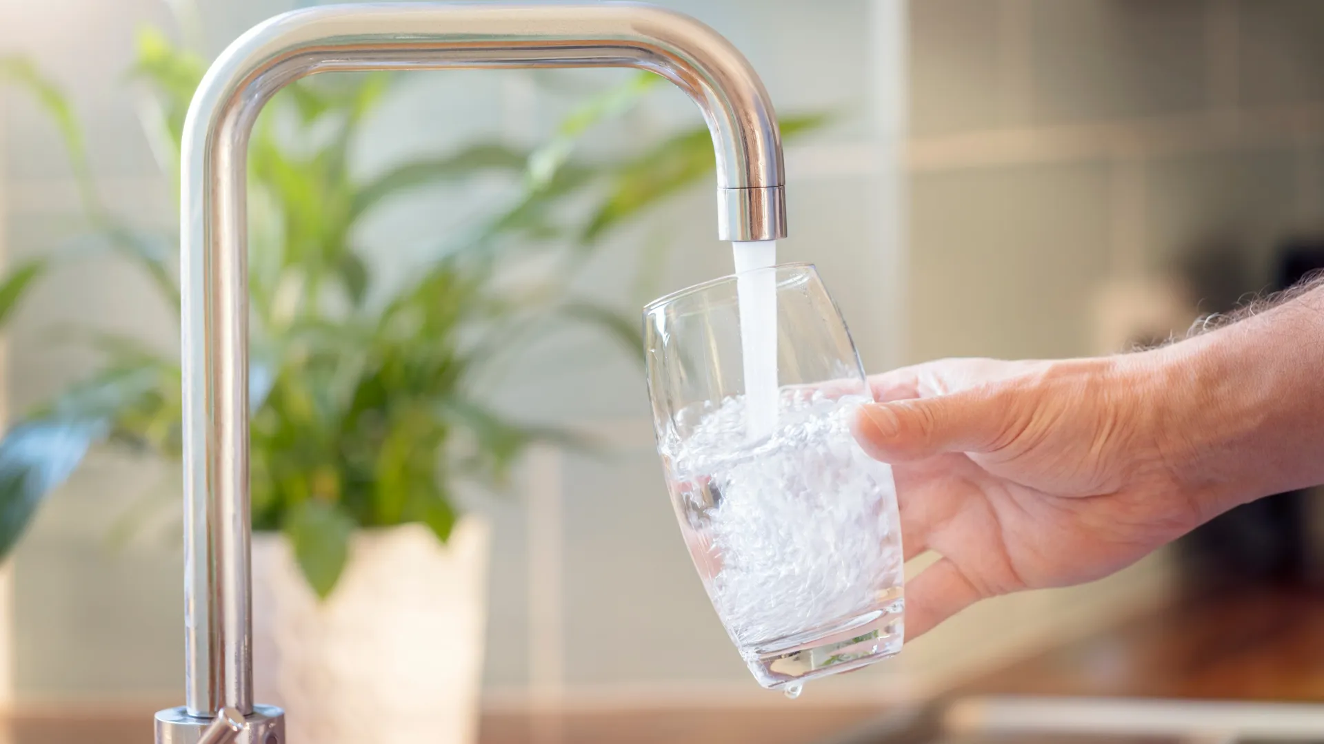 Wasserhahn, aus dem Wasser in Glas fließt